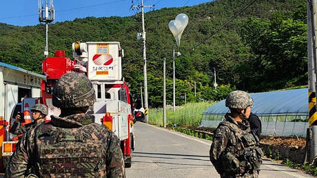 Balloons with trash presumably sent by North Korea, hang on electric wires as South Korean army soldiers stand guard in Muju, South Korea, on May 29, 2024.