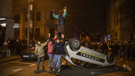 FILE PHOTO: Protestors damage a police car as they clash with law enforcement during demonstrations in Tbilisi, Georgia.