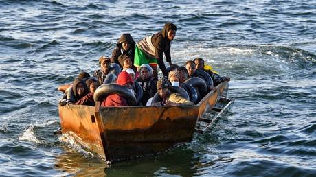 FILE PHOTO: Migrants sit in a makeshift boat.