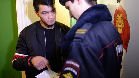 FILE PHOTO: A policeman checks papers of a migrant in Moscow.