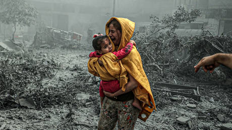 FILE PHOTO: A woman holding a girl reacts after Israeli airstrikes hit Ridwan neighborhood of Gaza City, Gaza.