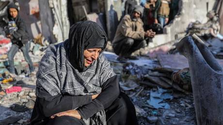 FILE PHOTO: A woman sits amongst damaged homes caused by Israeli air strikes, on January 18, 2024 in Rafah, Gaza.