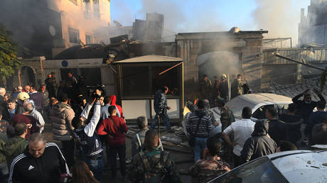 People gather in front of a residential building destroyed in Israeli airstrikes in the Mazzeh neighborhood of Damascus, Syria, on Nov. 14, 2024.