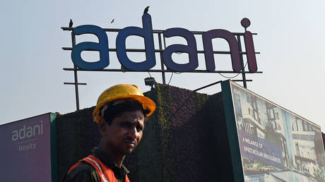 A construction worker walks below the Adani logo near a building construction site in Mumbai. Adani group is one of the India's largest multinational company with a diversified business portfolio.