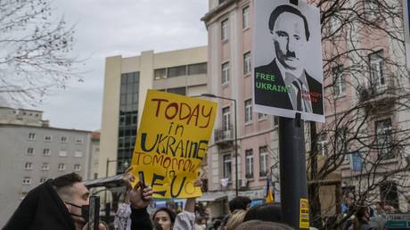 FILE PHOTO: Ukrainian residents display a poster in which Vladimir Putin looks like Adolf Hitler while protesting near the Russian Embassy on February 24, 2022, in Lisbon, Portugal.