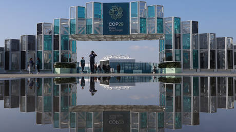 People are reflected in a puddle outside the conference venue prior to the UNFCCC COP29 Climate Conference on November 10, 2024 in Baku, Azerbaijan.