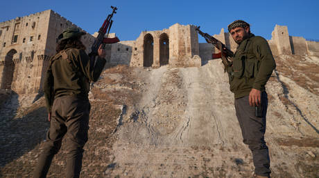 Syrian opposition fighters pose for a photo in front of the ancient citadel of Aleppo after taking control of the Syrian city on December 1, 2024.