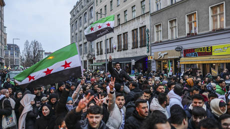 Expatriate Syrians gather with flags to celebrate the fall of the Assad regime in Syria on December 8, 2024 in Berlin, Germany.