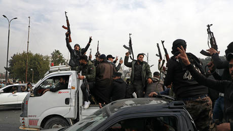 People wave guns in the air, as they gather to celebrate the fall of the Syrian regime in Umayyad Square on December 8, 2024 in Damascus, Syria.