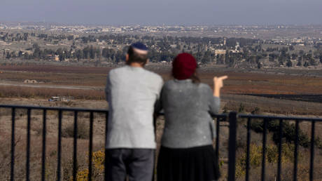 An Israeli couple look into Syria from the Israeli-occupied Golan Heights, December 9, 2024