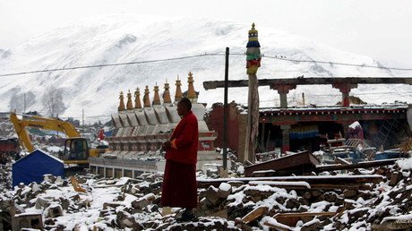 A Tibetan monk stands watch as workers clear the rubble following an earthquake in  Qinghai on April 22, 2010.© AFP