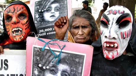 FILE PHOTO: An elderly Indian woman (C) along with demonstators wearing masks protests ouside the Bhopal court, 29 may 2003 during the hearing of the Bhopal gas tragedy case.