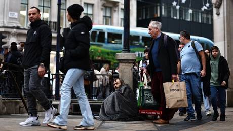 Members of the public walk past a rough sleeper at Oxford Circus in London, England, December 27, 2023