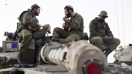 FILE PHOTO: Soldiers play guitar while sitting on tanks near the border with Gaza in southern Israel.