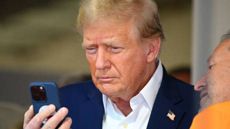 Donald Trump talks on the phone in the McLaren garage prior to the F1 Grand Prix of Miami in Miami, Florida, May 5, 2024