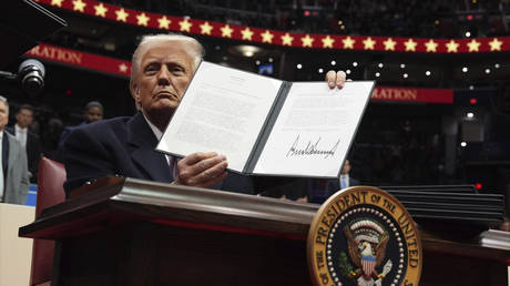 President Donald Trump signs an executive order as he attends an indoor Presidential Inauguration parade event at Capital One Arena, Monday, Jan. 20, 2025, in Washington.